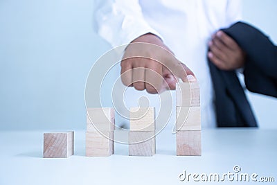 Businessman touches the woodblocks placed on the table Stock Photo