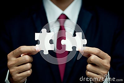 Businessman try to connect two piece of jigsaw puzzle Stock Photo