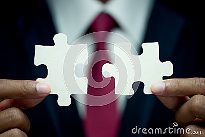 Businessman try to connect two piece of jigsaw puzzle Stock Photo