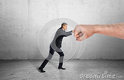 Businessman trying to resist huge male fist and move it away on grey background Stock Photo