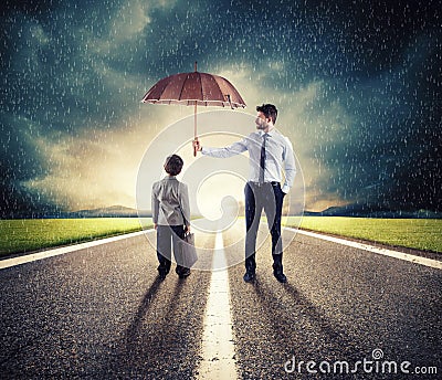 Businessman with umbrella that protect a child. Concept of young economy and startup protection Stock Photo