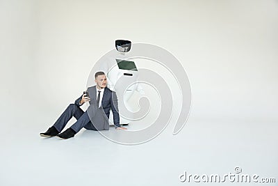 Businessman uses a smartphone while sitting on the floor next to a robot. Modern Robotic Technologies. Humanoid Stock Photo