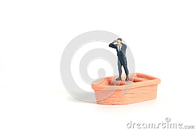 Businessman using binoculars standing above boat. Miniature tiny people toys photography. isolated on white background Stock Photo