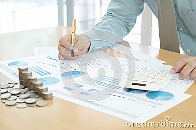 Businessman using calculator, tablet with stacked coins arranged Stock Photo