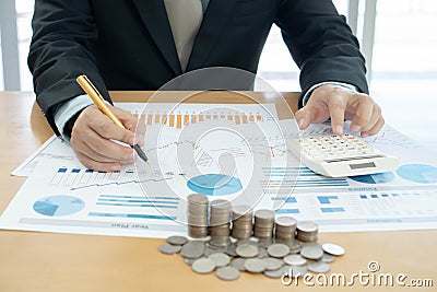 Businessman using calculator and tablet with stacked coins arranged Stock Photo