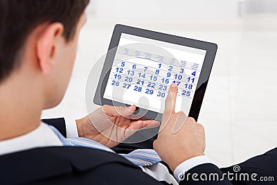 Businessman Using Calendar On Digital Tablet In Office Stock Photo