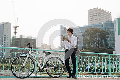 Businessman using digital tablet outdoors. Man looking at tablet and standing next to the bike leaning to wall. Space for copy Stock Photo