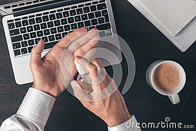 Businessman using disinfectant spray to disinfect hands while working office desk Stock Photo