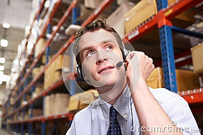 Businessman Using Headset In Distribution Warehouse Stock Photo