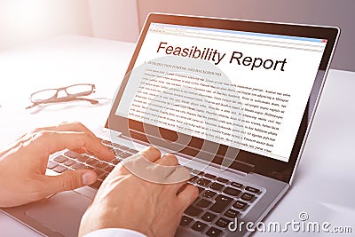 Man Typing Feasibility Report On Laptop Stock Photo