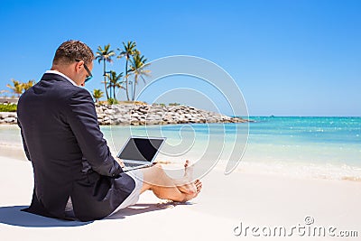 Businessman using laptop computer on tropical beach Stock Photo