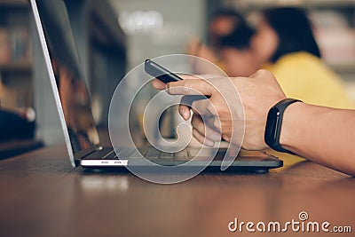 Businessman using laptop and typing on mobile smart phone, business people with technology concept. Close up hand man working. Stock Photo