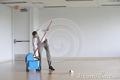 Businessman Using Mop In Empty Room Stock Photo