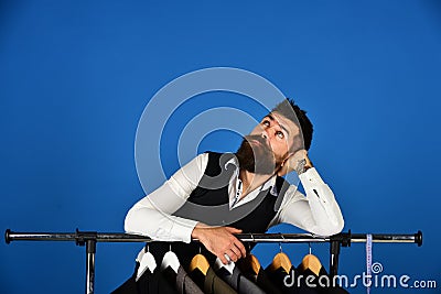 Businessman in vest near row of suits in shop. Stock Photo