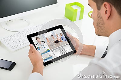 Businessman Videoconferencing With Colleagues On Digital Tablet Stock Photo