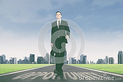 Businessman walking above opportunity word on the road Stock Photo