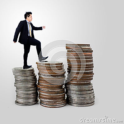 Businessman walking on coins stack on gray Stock Photo