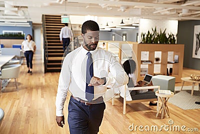 Businessman Walking Through Modern Office Checking Health Data On Smart Watch Stock Photo