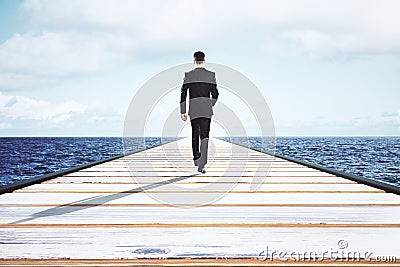 Businessman walking on a straight road to the horizon Stock Photo