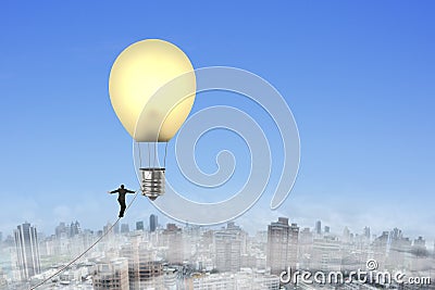Businessman walking tightrope toward lightbulb shape hot air bal Stock Photo