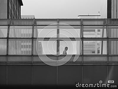 Businessman walks through bridge connecting office buildings Editorial Stock Photo