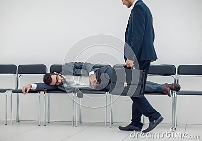 Businessman walks past a sleeping visitor Stock Photo