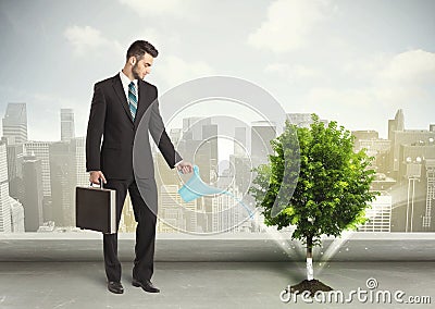 Businessman watering green tree on city background Stock Photo