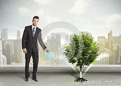 Businessman watering green tree on city background Stock Photo