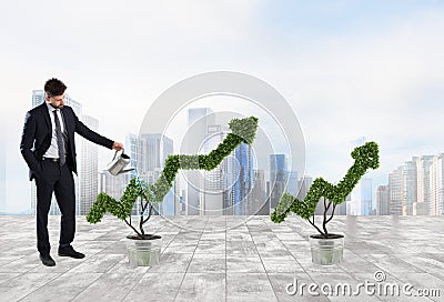 Businessman that watering a plant with a shape of arrow. Concept of growing of company economy . Stock Photo