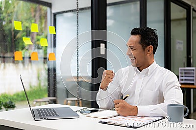 A businessman wearing a formal suit is at work. He sat in front of his laptop computer, Stock Photo