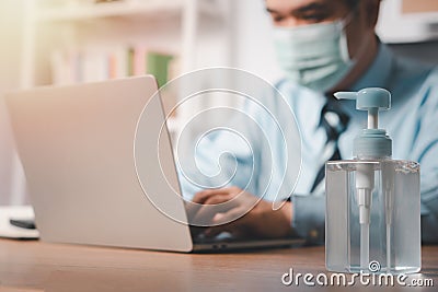 Businessman wearing a mask and have hand sanitizer on his desk for prevention or antibacterial hygiene and Coronavirus disease at Stock Photo