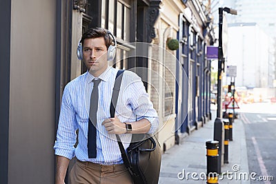 Businessman Wearing Wireless Headphones Walking To Work Stock Photo