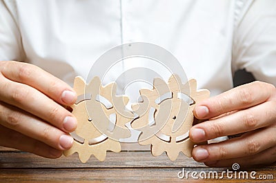 Businessman in white shirt connects two wooden gears. Symbolism of establishing business processes and communication. Improving Stock Photo