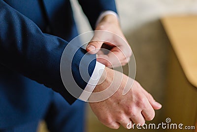 Businessman in a white shirt straightens cuffs, standing at the window in natural light. Man buttons cuff-link on French Stock Photo