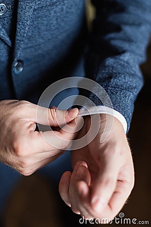 Businessman in a white shirt straightens cuffs, standing at the window in natural light. Man buttons cuff-link on French Stock Photo