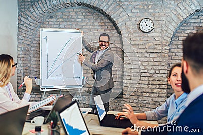 Businessman At Whiteboard Giving Presentation In Boardroom Stock Photo