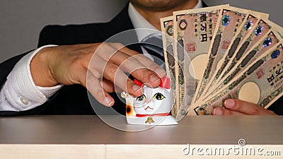 A businessman who has a lot of money and strokes a beckoning cat Stock Photo