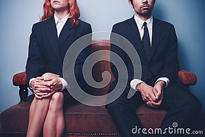 Businessman and woman waiting on sofa in lobby Stock Photo