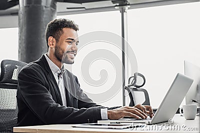 Businessman working on computer. Young smiling man using laptop in the office. Internet marketing, finance, business concept Stock Photo