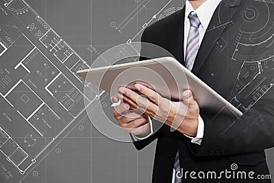 Businessman working on digital tablet with Architectural blueprint plan drawing background, architect, real estate business Stock Photo