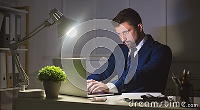 Businessman working on laptop in dark office Stock Photo