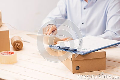 Businessman working with mobile phone and packing brown parcels box at home office Stock Photo
