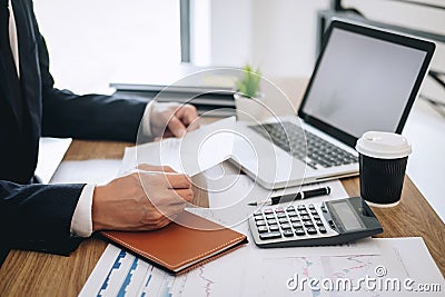 Businessman working new project on laptop computer with report document and analyze, calculating financial data on graph documents Stock Photo