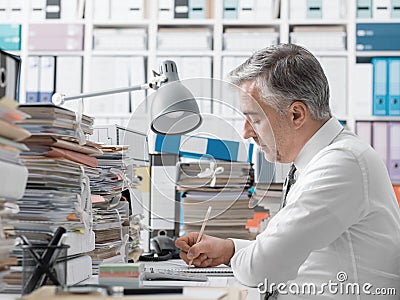 Businessman working in the office and piles of paperwork Stock Photo