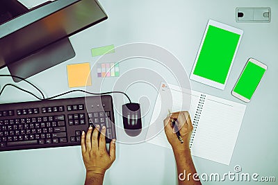 Businessman working by using computer and also taking memo on notebook Stock Photo