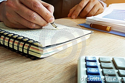 Businessman writing financial results in book. Bookkeeping concept. Stock Photo