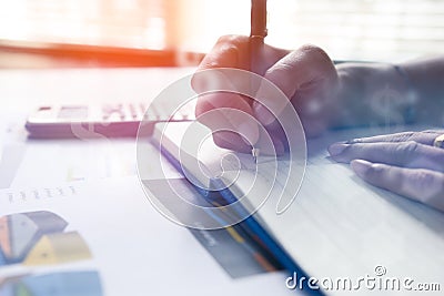 Businessman writing on notebook on wooden table, People are recording accounting data calculated from a calculator. Stock Photo