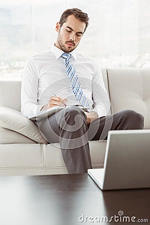 Businessman writing notes in living room Stock Photo