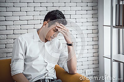 Businessman young asian having a migraine or headache, struggle with dizziness on sitting couch at home Stock Photo