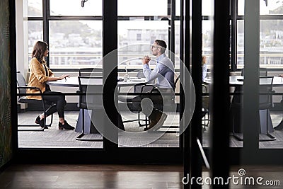 A businessman and young woman meeting for a job interview, full length, seen through glass wall Stock Photo